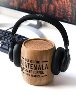 brown Guatemala wooden mug and black JBL headphones on it