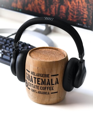 brown Guatemala wooden mug and black JBL headphones on it