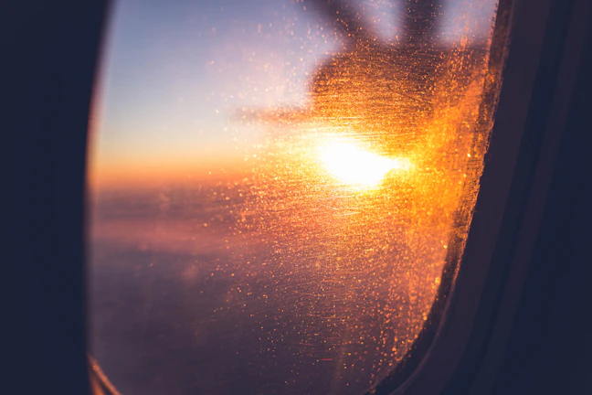 A vibrant sunrise over a tropical island viewed from an airplane window.