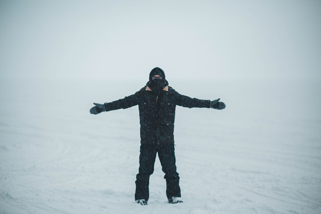 man in black jacket and pants stands on snow covered ground