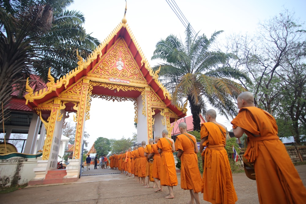 man wearing orange monk robe walking on arch