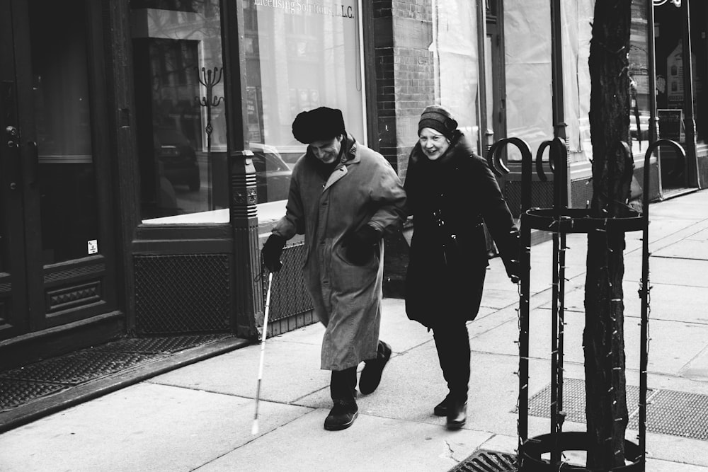 man and woman walking on street in front of stores