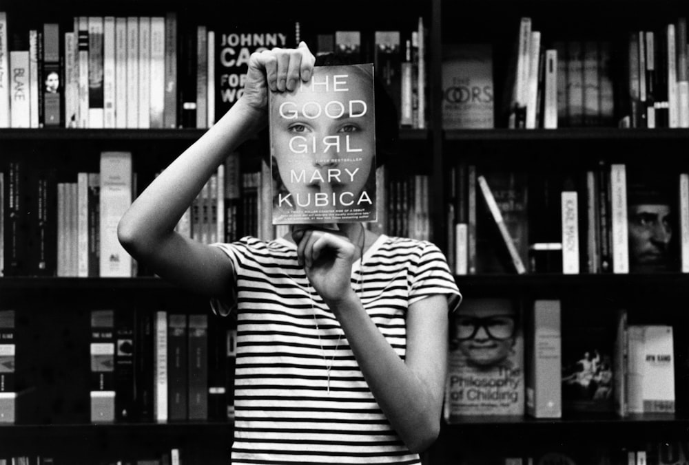 woman in striped shirt holds book in library