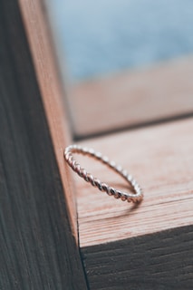 A close-up of a beautifully crafted unisex ring on a wooden surface.