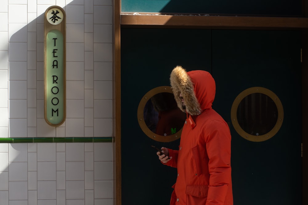 person wearing orange hoodie walking outside store door