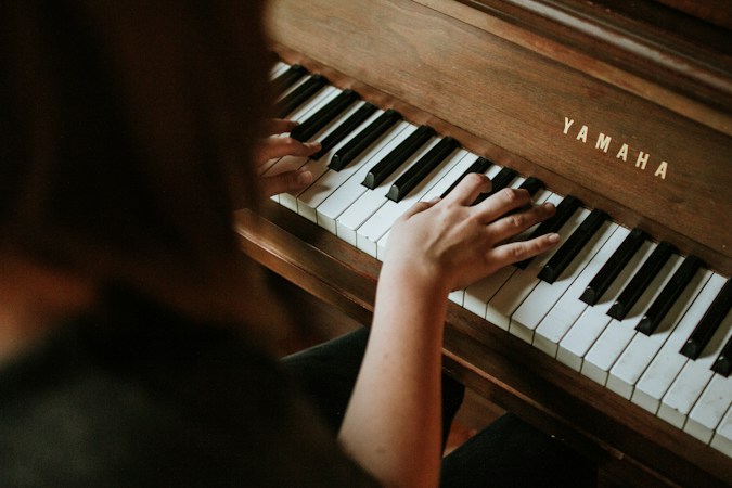 A woman playing an upright piano at home, the kind of family instrument a Las Vegas piano tuner visits year after year