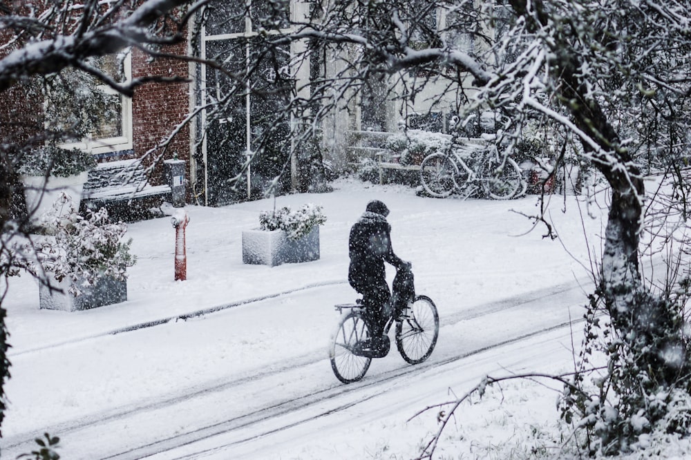 man riding bicycle on snow covered ground