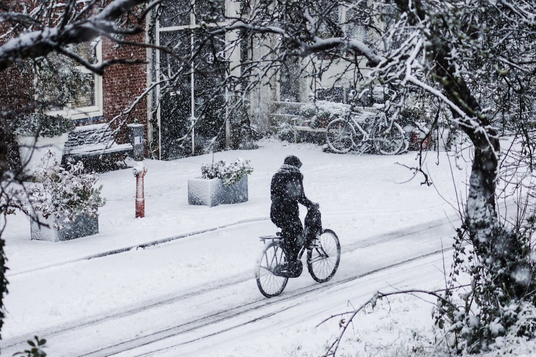 man riding bicycle on snow covered ground,