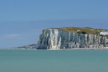 white and green high-rise hill beside body of water during daytime