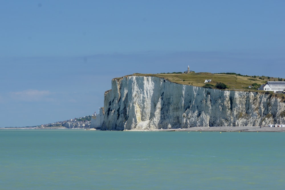 white and green high-rise hill beside body of water during daytime