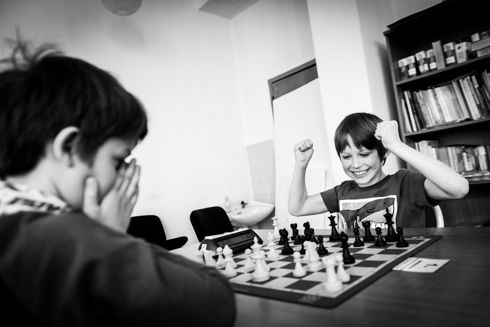 two boy playing chess grayscale photo
