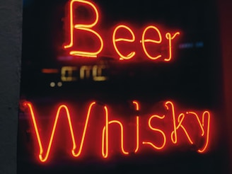 Neon signage displays the words Beer and Whisky in bright red against a dark background.