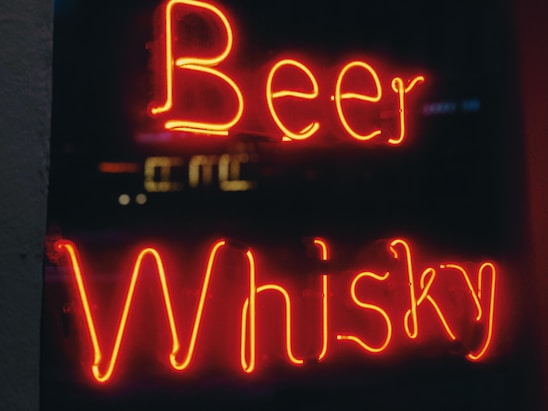 Neon signage displays the words Beer and Whisky in bright red against a dark background.