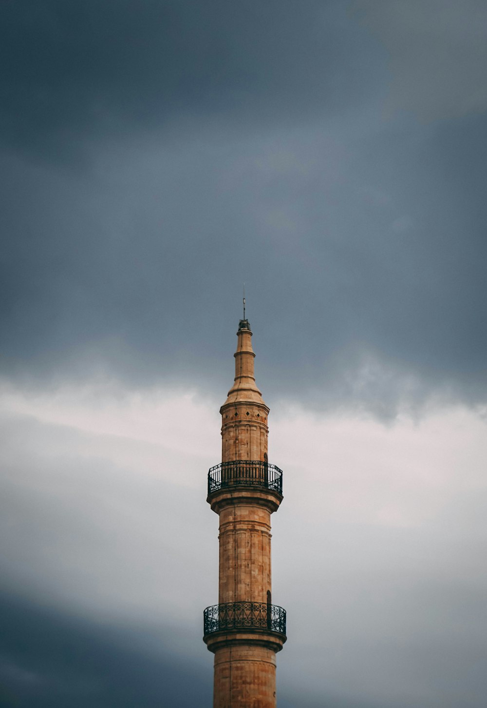 brown brick tower building under grey clouds