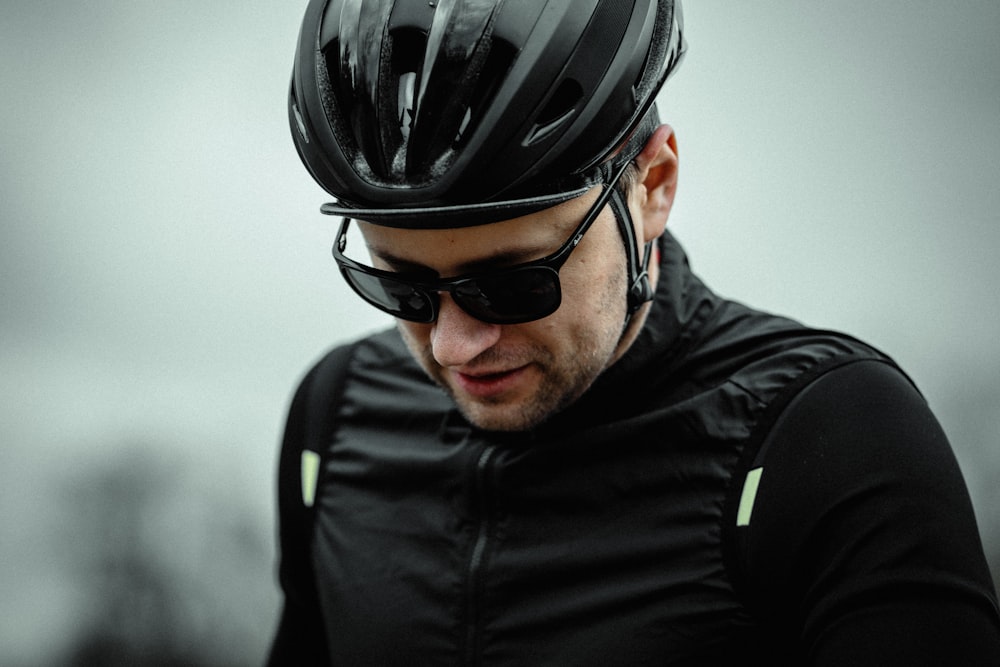 homem vestindo jaqueta zip-up preta e capacete de bicicleta