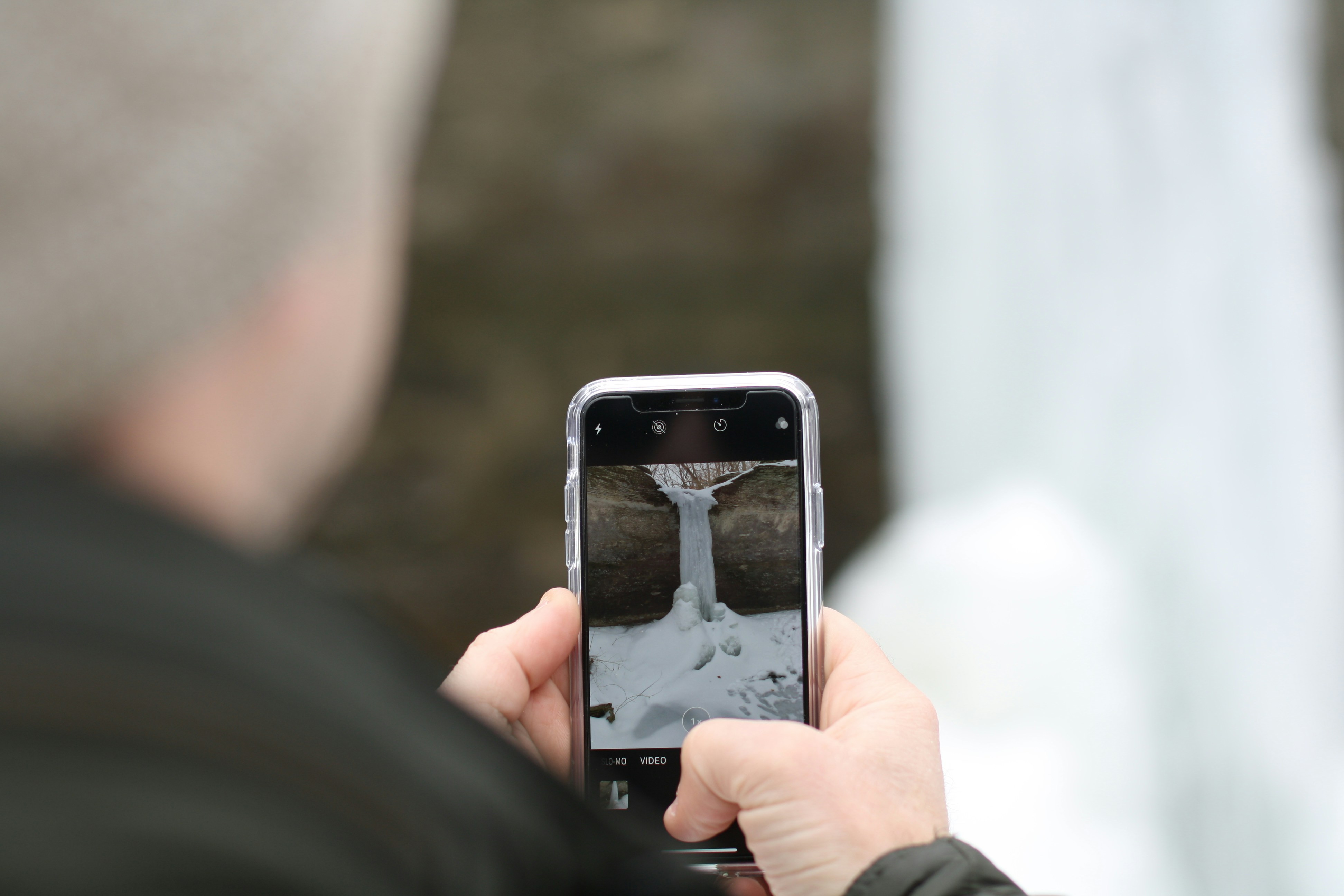 of a person taking a photo of a cracked sidewalk with their phone. - parking lot fall