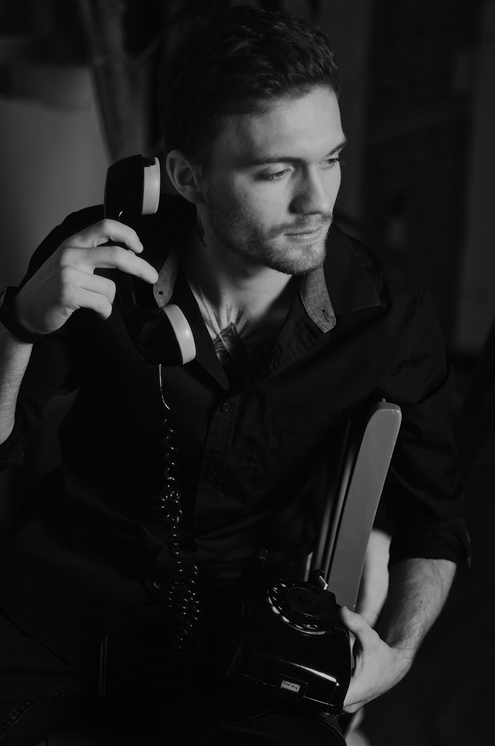 grayscale photo of man holding telephone