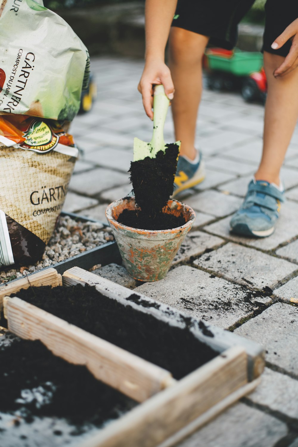 person putting soil inside brown planter