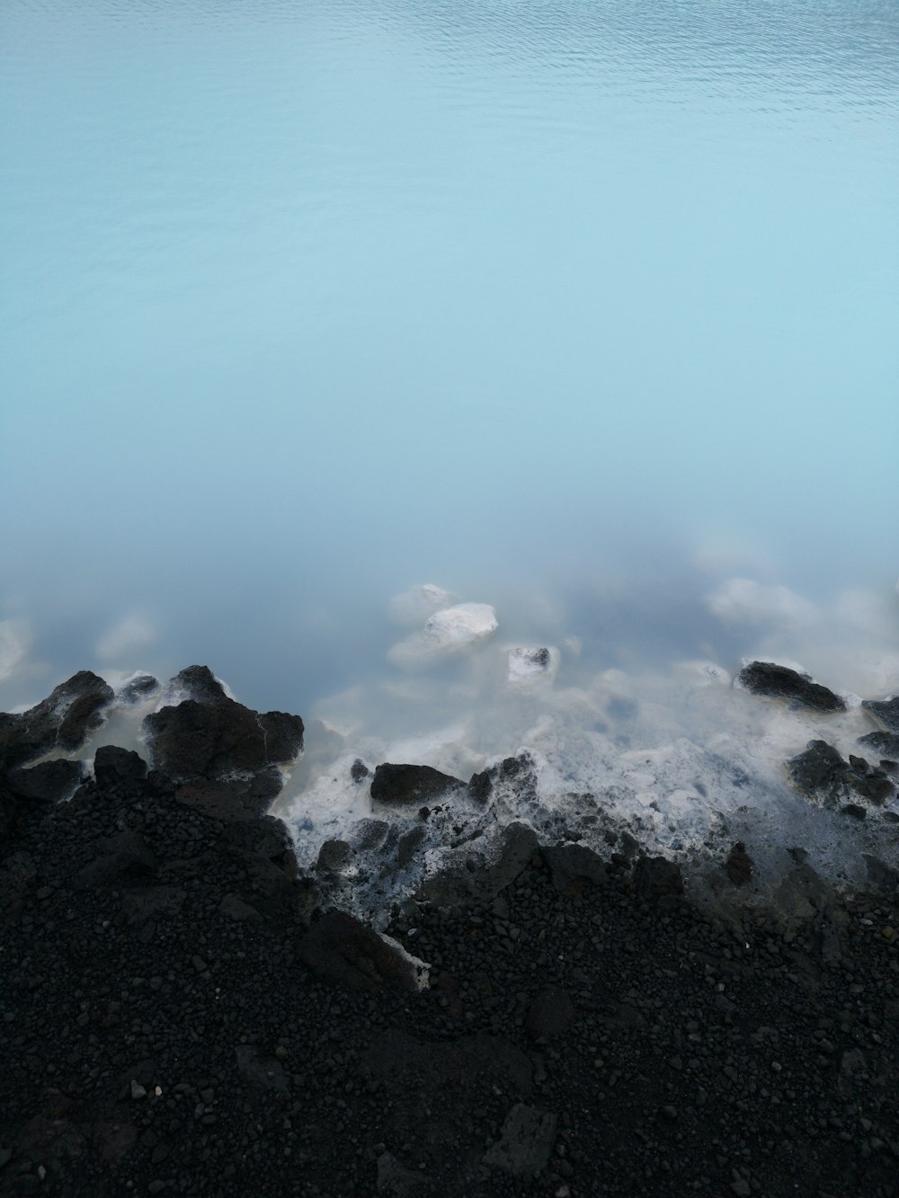 body of water beside black rocks