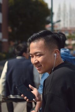 Photo of a young person using an Android device outdoors, smiling.