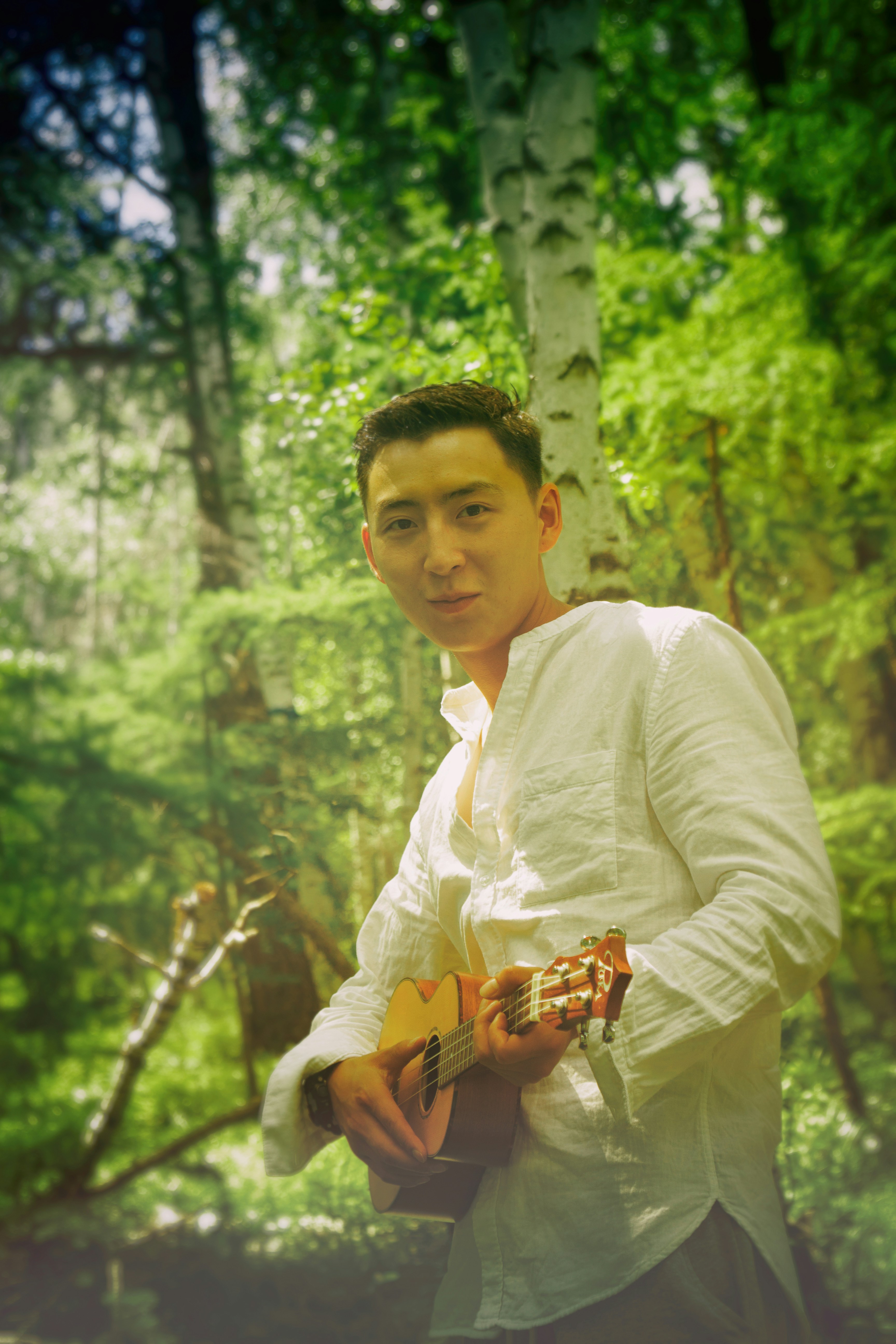 man wearing white dress shirt holding brown ukulele
