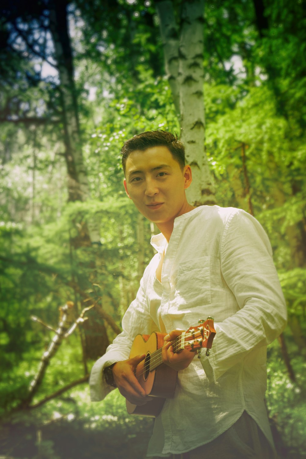 man wearing white dress shirt holding brown ukulele