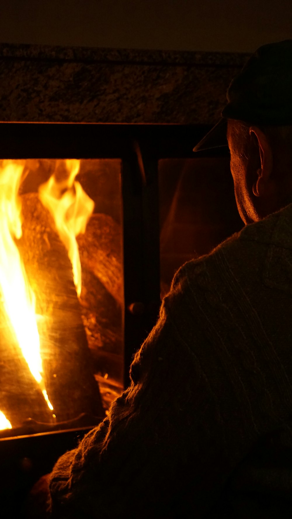 a man sitting in front of a fire in a fireplace
