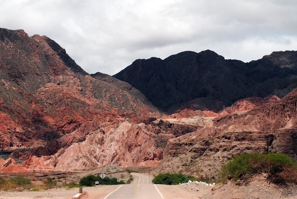 gray concrete road across mountain during daytime