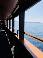 A minimalistic modern boat interior with wide windows overlooking the sea.