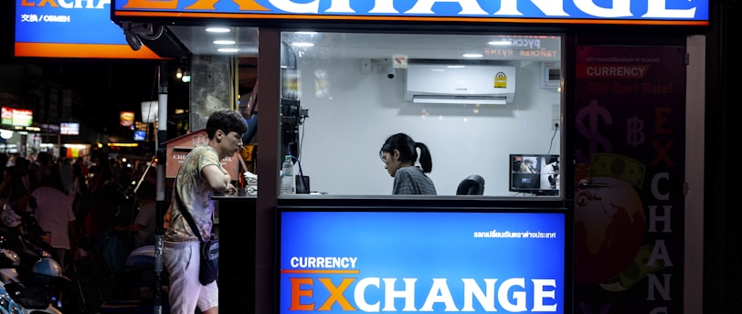 man in gray short standing near counter of currency exchange