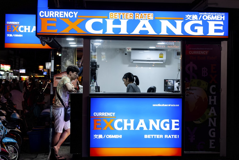 hombre en gris corto de pie cerca del mostrador de cambio de divisas