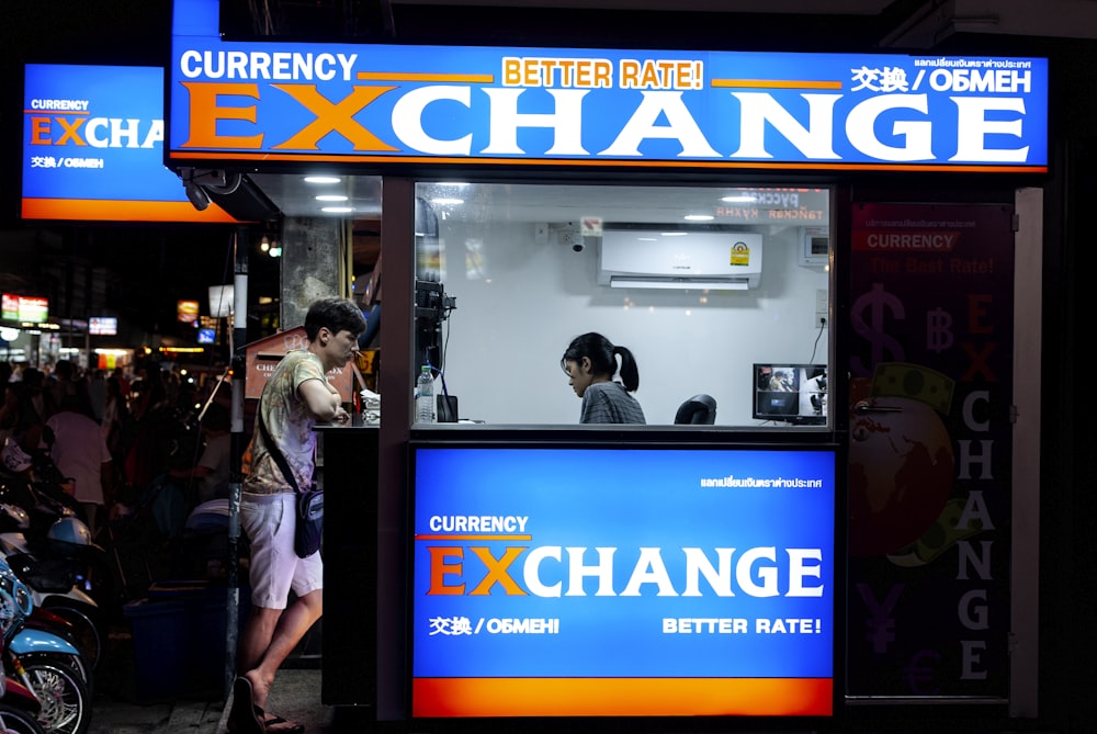 man in gray short standing near counter of currency exchange