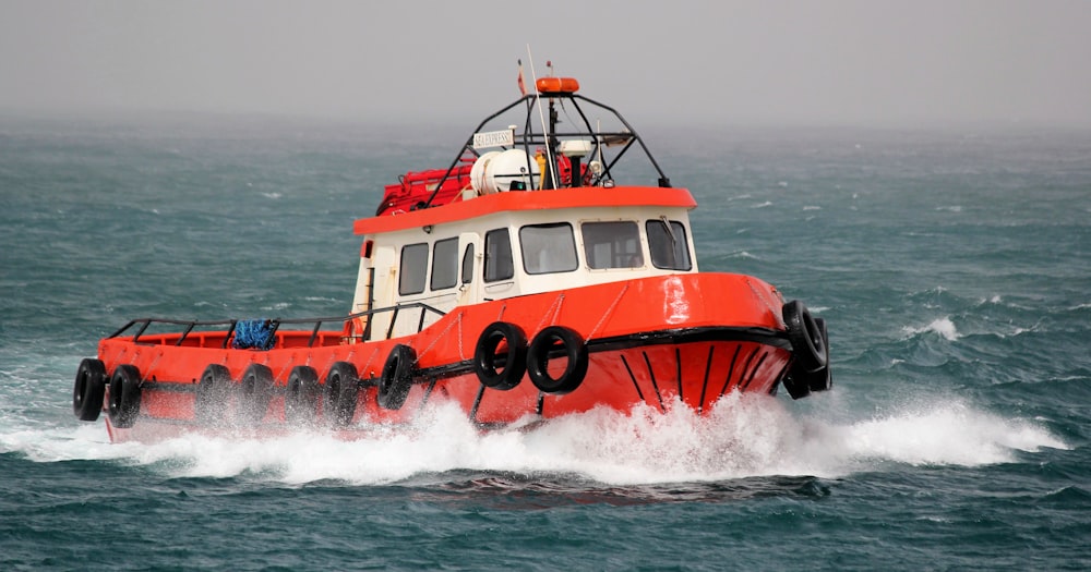 Bateau à moteur orange et blanc naviguant de jour