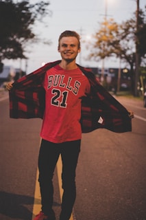 Smiling customer wearing bull & bear jeans, standing casually in a sunlit urban street.