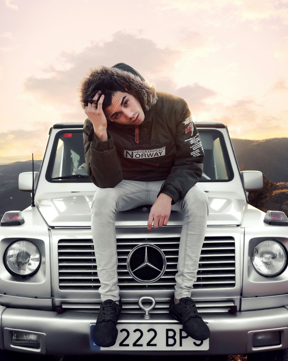 man sitting on silver Mercedes-Benz vehicle