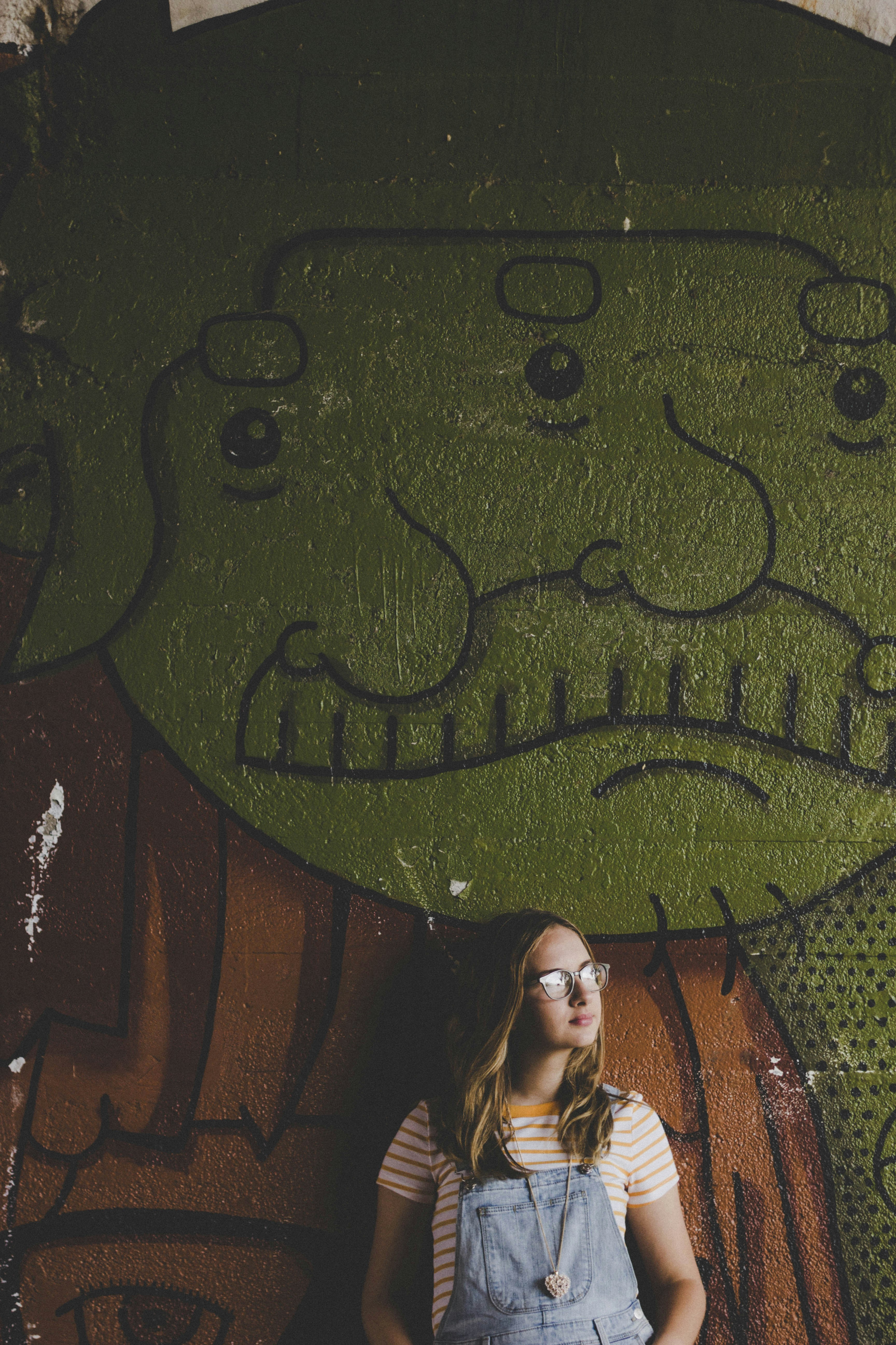 woman standing beside brown and green concrete wall