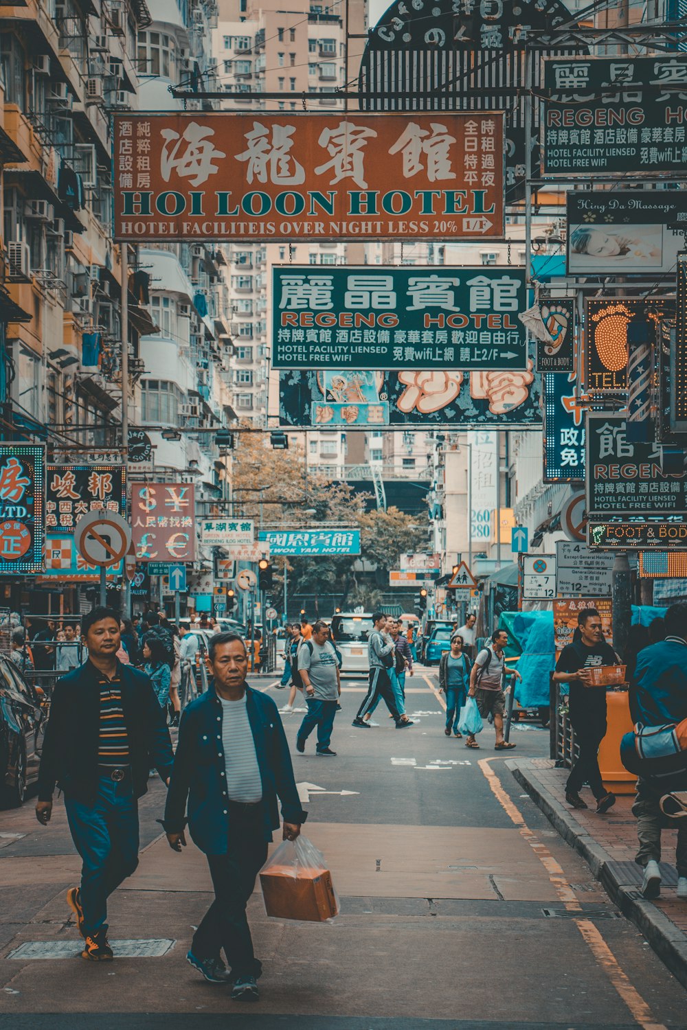 people walking on road under Kanji script signs during daytime