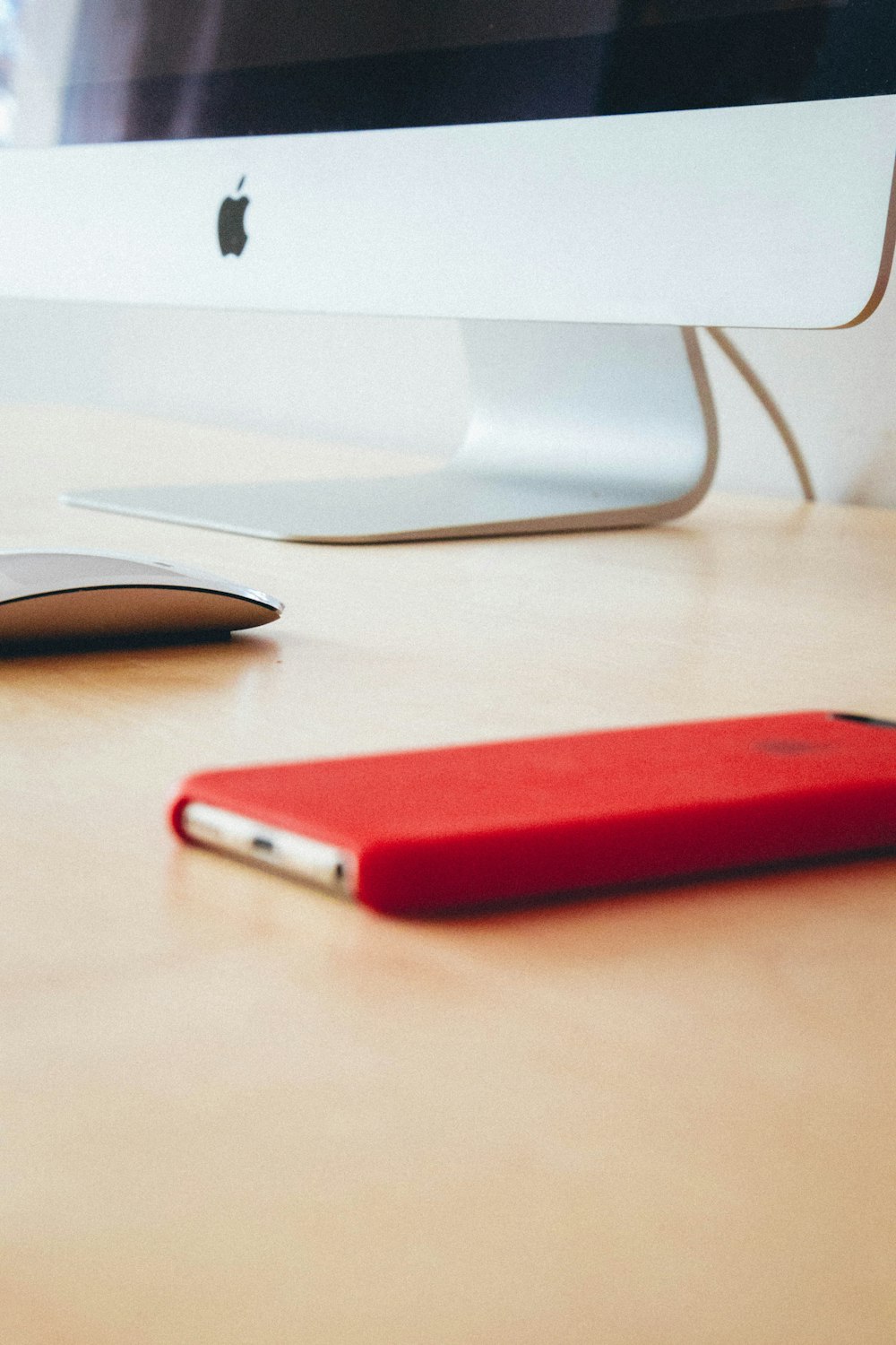 silver smartphone with red case on brown wooden table