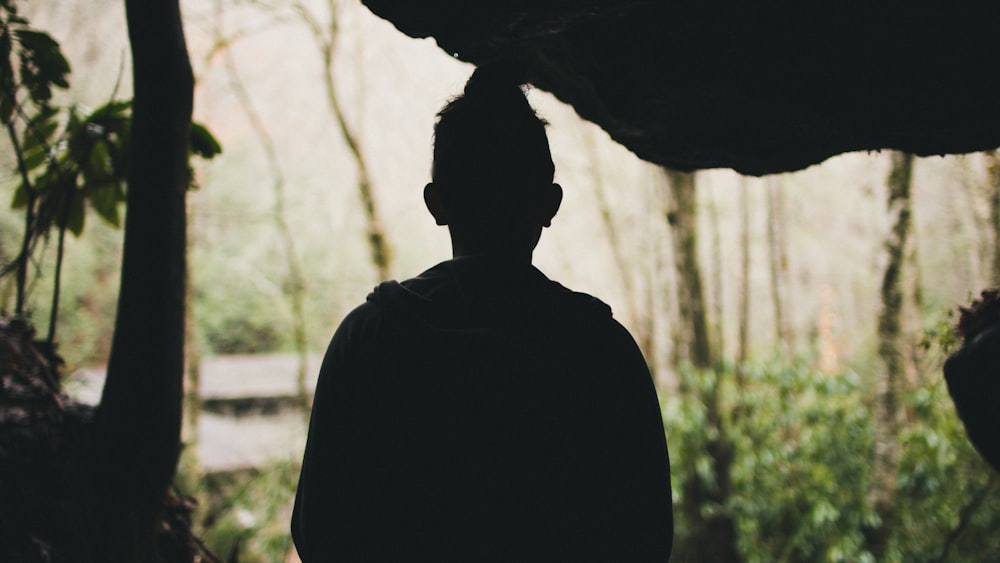 silhouette photography of man standing in front of trees