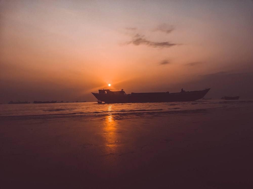 silhouette photography of boat with sunset background