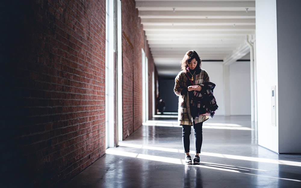 건물에 서 있는 검은색과 갈색 재킷을 입은 여자