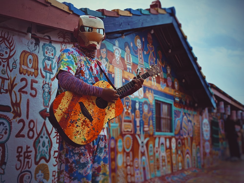 uomo che indossa una maschera facciale marrone che tiene la chitarra