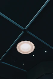 A sleek modern ceiling light casting soft light over a minimalist dining area.