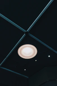 A sleek modern ceiling light casting soft light over a minimalist dining area.