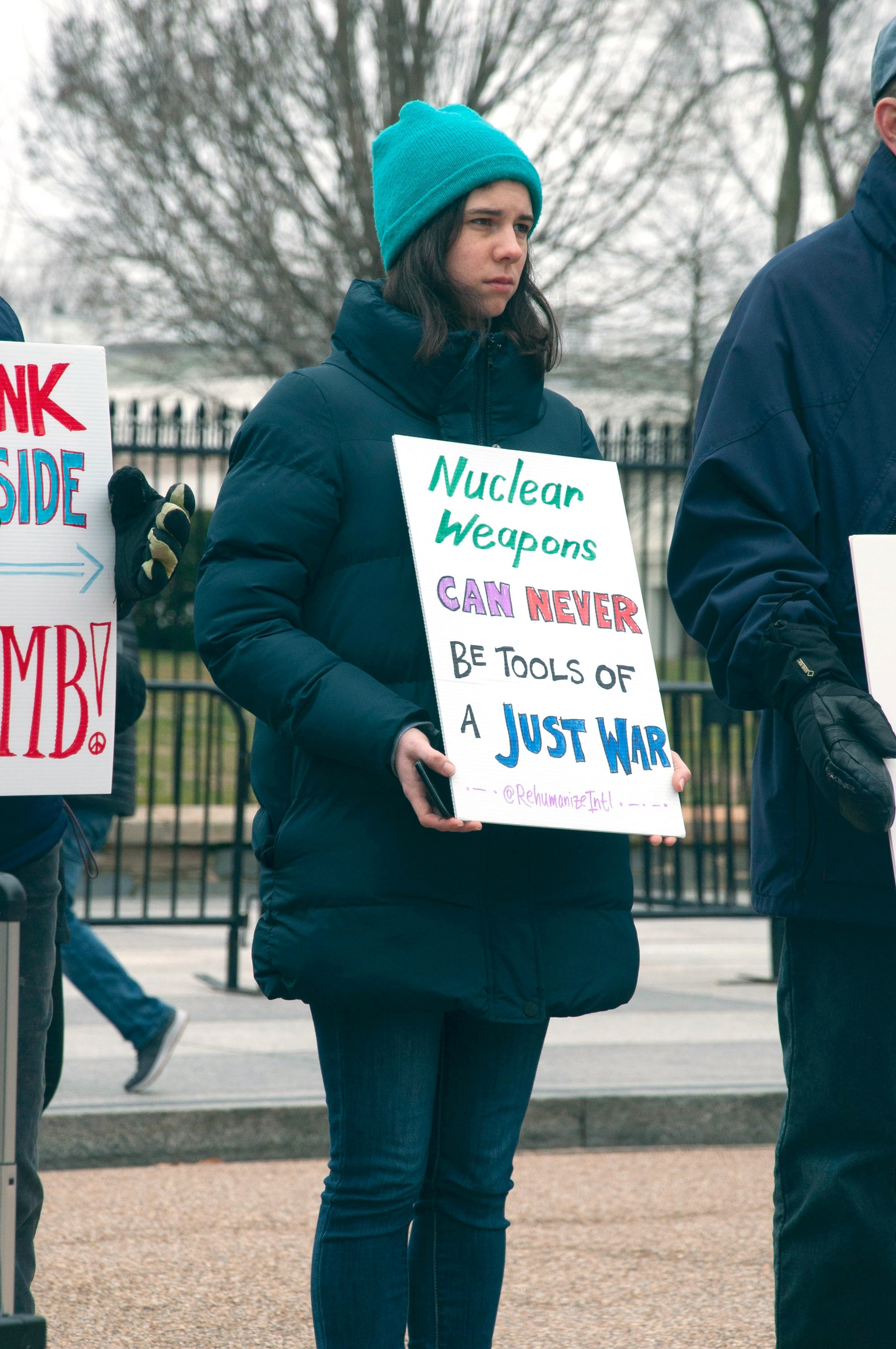 woman holding signage near green leaf trees