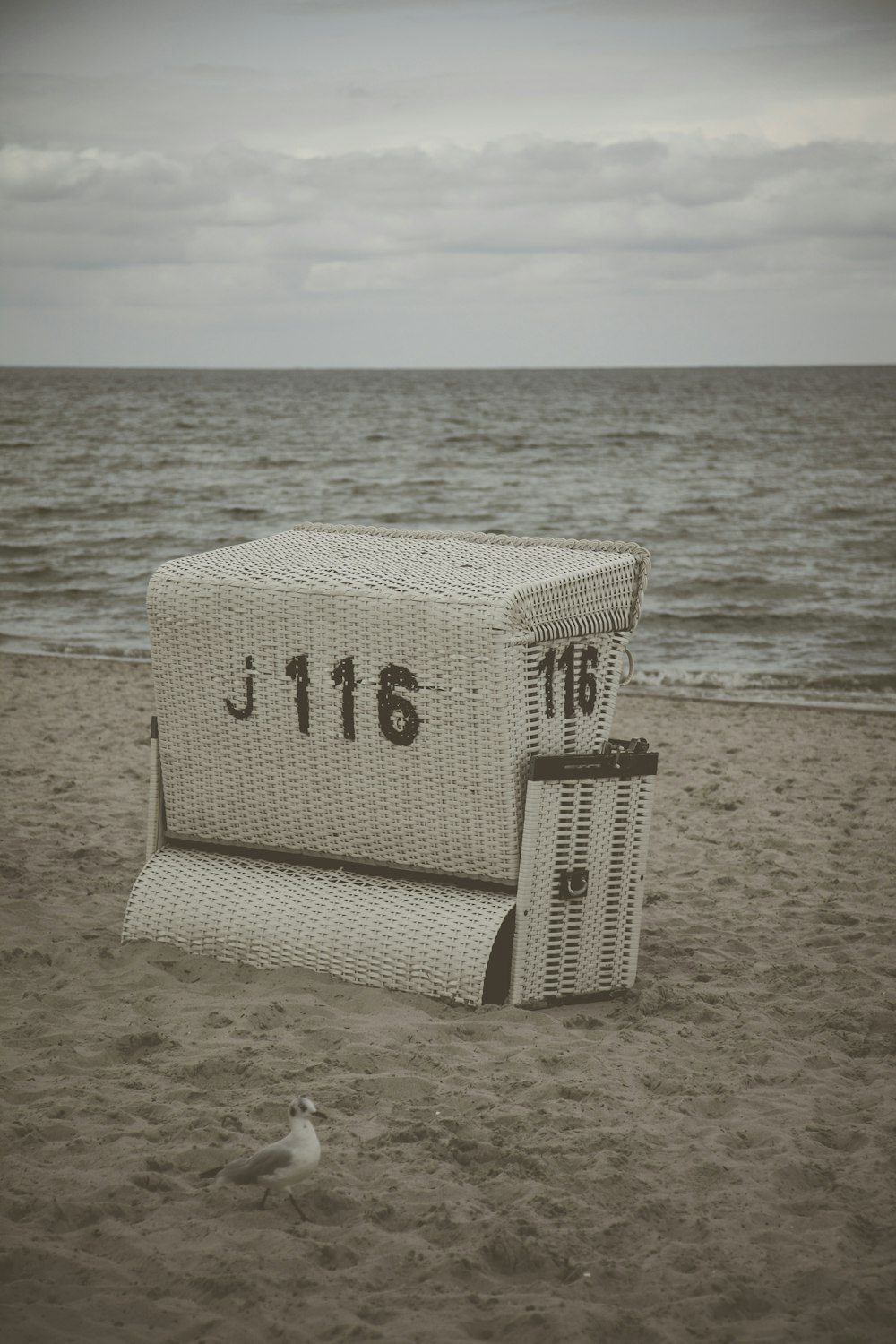 white wicker basket numbered 116 on beach