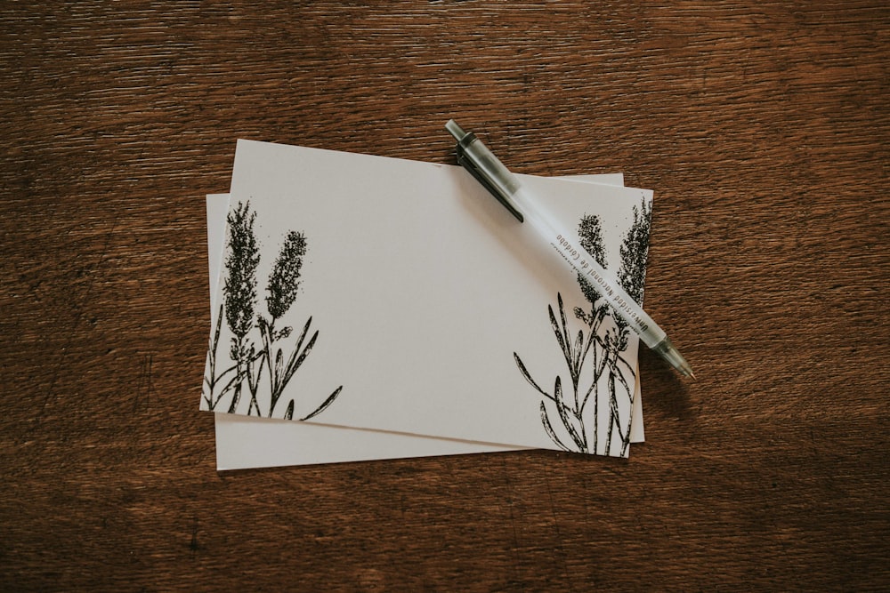 white pen on top of two white and black floral stationeries