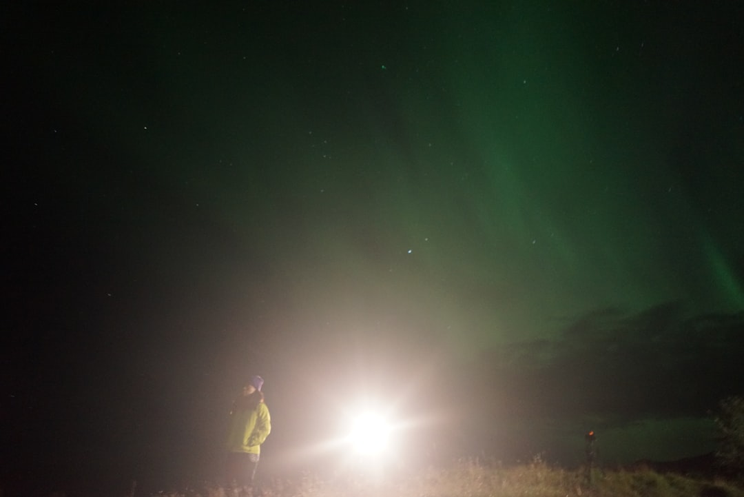 man standing under green sky phenomenon during nighttime