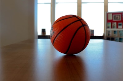 Basketball bouncing on a polished wooden court with hoop in background