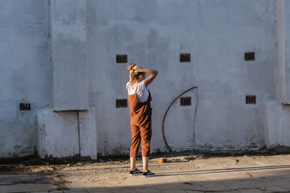 woman wearing white t-shirt and brown overalls near building during daytime